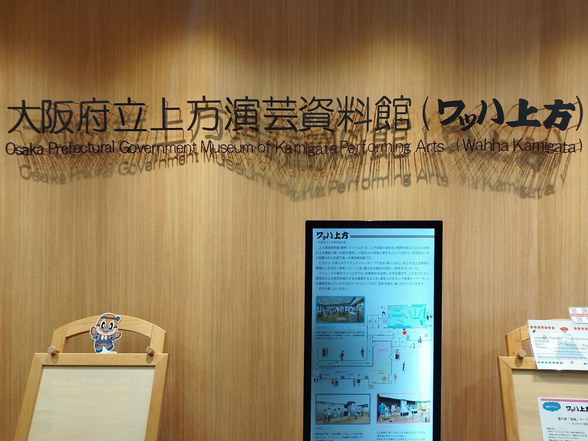 「大阪府立上方演芸資料館(ワッハ上方)」の壁の看板と展示の説明。